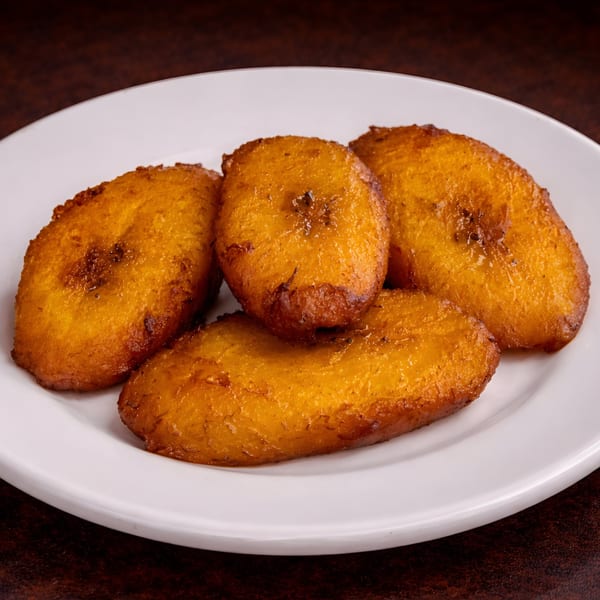 Four golden-brown fried sweet plantains, known as maduros, on a white plate.