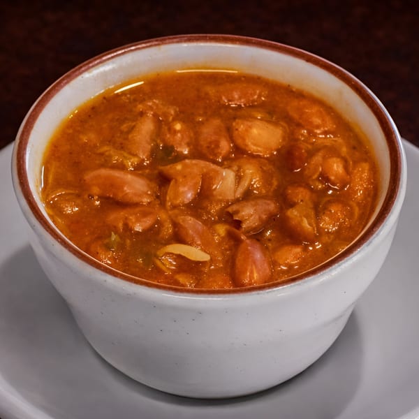 A white bowl filled with Numero Uno Restaurant's Cuban red bean soup, garnished with onions.